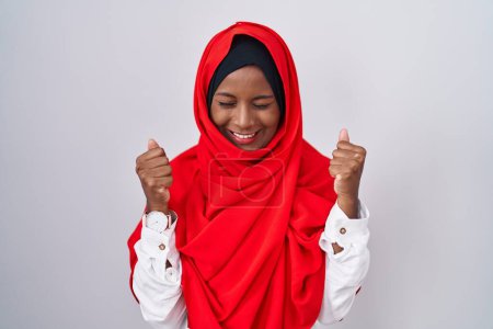 Téléchargez les photos : Jeune femme arabe portant l'écharpe traditionnelle islamique hijab excité pour le succès avec les bras levés et les yeux fermés célébrant la victoire en souriant. concept gagnant. - en image libre de droit