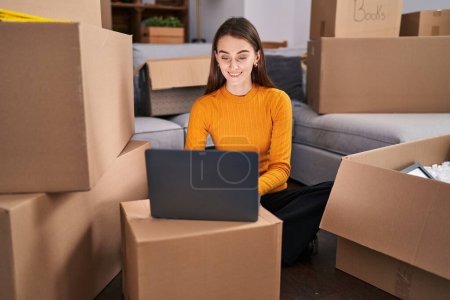 Photo for Young caucasian woman using laptop sitting on floor at new home - Royalty Free Image