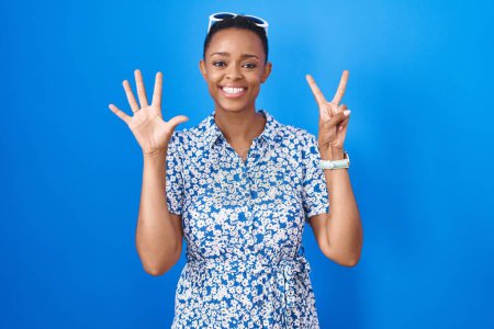 Téléchargez les photos : African american woman standing over blue background showing and pointing up with fingers number seven while smiling confident and happy. - en image libre de droit