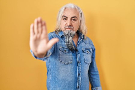 Photo for Middle age man with grey hair standing over yellow background doing stop sing with palm of the hand. warning expression with negative and serious gesture on the face. - Royalty Free Image