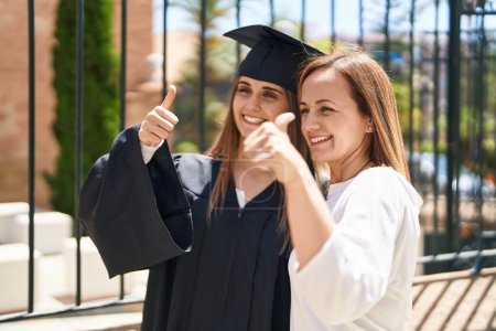 Foto de Dos mujeres madre e hija graduada haciendo buen gesto en la universidad del campus - Imagen libre de derechos