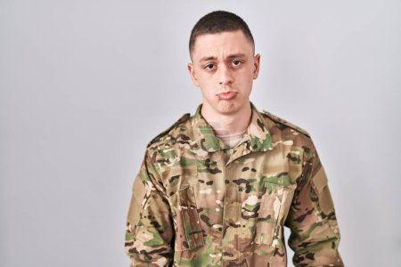 Foto de Joven vestido con uniforme camuflaje del ejército deprimido y preocupado por la angustia, llorando enojado y asustado. expresión triste. - Imagen libre de derechos