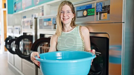Photo for Young blonde woman smiling confident holding empty basket at laundry room - Royalty Free Image