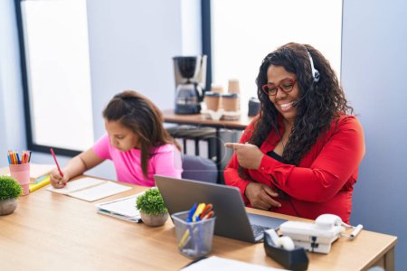 Photo for Mother and young daughter at the office working and doing homework smiling happy pointing with hand and finger - Royalty Free Image
