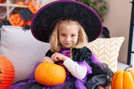 Foto de Adorable chica rubia con disfraz de bruja teniendo fiesta de Halloween en casa - Imagen libre de derechos