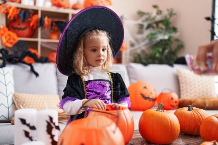 Foto de Adorable chica rubia con disfraz de bruja teniendo fiesta de Halloween en casa - Imagen libre de derechos