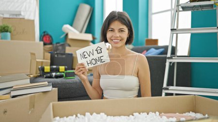 Photo for Young beautiful hispanic woman smiling confident holding new home paper at new home - Royalty Free Image
