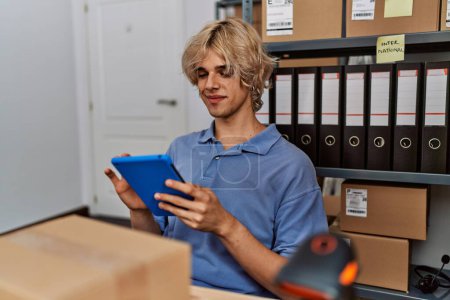Téléchargez les photos : Jeune homme blond ecommerce travailleur d'affaires en utilisant le pavé tactile au bureau - en image libre de droit