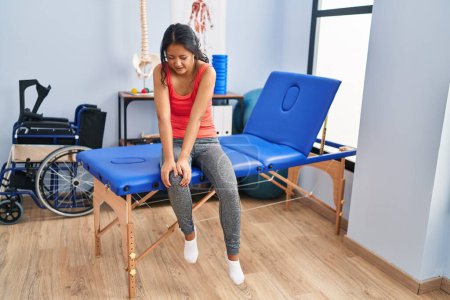 Young chinese woman patient having rehab session suffering for knee pain at rehab clinic