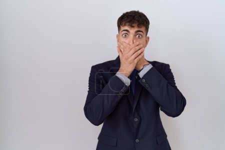 Foto de Un joven empresario hispano vestido de traje y corbata sorprendió cubriendo la boca con las manos por error. concepto secreto. - Imagen libre de derechos