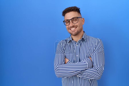 Téléchargez les photos : Homme hispanique à la barbe portant des lunettes heureux visage souriant avec les bras croisés en regardant la caméra. personne positive. - en image libre de droit