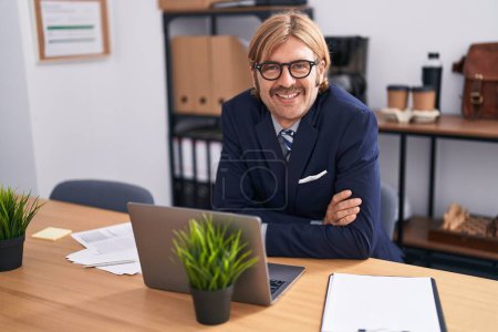 Photo for Young blond man business worker sitting with arms crossed gesture at office - Royalty Free Image