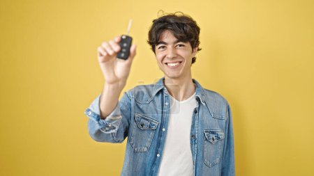 Photo for Young hispanic man smiling confident holding key of new car over isolated yellow background - Royalty Free Image