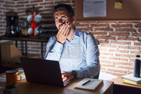 Photo for Hispanic man with beard working at the office at night bored yawning tired covering mouth with hand. restless and sleepiness. - Royalty Free Image