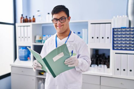 Foto de Síndrome de Down hombre con uniforme científico lectura portátil en el laboratorio - Imagen libre de derechos