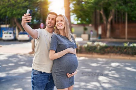 Foto de Hombre y mujer pareja esperando bebé hacer selfie por teléfono inteligente en la calle - Imagen libre de derechos