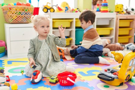 Foto de Adorable niño y niña jugando juego de supermercado y con juguetes de coche en el jardín de infantes - Imagen libre de derechos