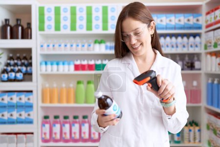 Foto de Joven hermosa mujer farmacéutico escaneo botella de medicamentos en la farmacia - Imagen libre de derechos