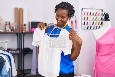Photo for Middle age african american woman tailor smiling confident holding t shirt at atelier - Royalty Free Image