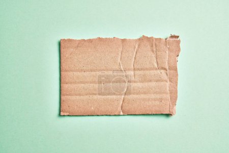 Téléchargez les photos : Un morceau de carton déchiré sur fond vert isolé - en image libre de droit
