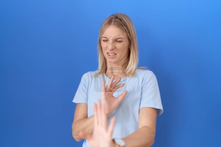 Foto de Mujer caucásica joven usando casual camiseta azul expresión disgustada, disgustada y temerosa haciendo asqueroso cara porque la reacción de aversión. - Imagen libre de derechos