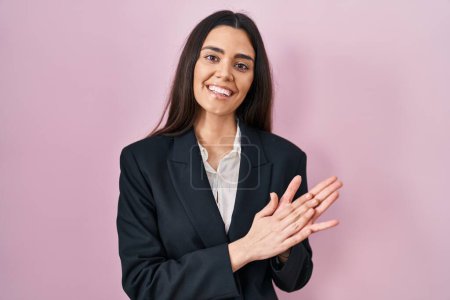 Téléchargez les photos : Jeune femme brune portant un style d'affaires sur fond rose applaudissements et applaudissements heureux et joyeux, souriant mains fières ensemble - en image libre de droit