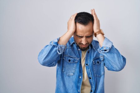Téléchargez les photos : Jeune homme hispanique debout sur fond isolé souffrant de maux de tête désespérés et stressés parce que la douleur et la migraine. mains sur la tête. - en image libre de droit