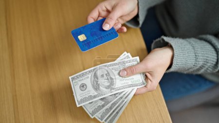 Foto de Joven rubia sosteniendo tarjeta de crédito y dólares en la oficina - Imagen libre de derechos