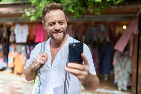 Foto de Middle age man tourist using smartphone at street market - Imagen libre de derechos