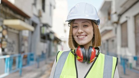Téléchargez les photos : Jeune femme blonde architecte souriant confiant debout dans la rue - en image libre de droit