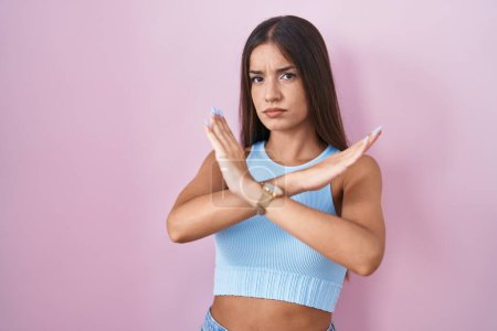 Photo for Young brunette woman standing over pink background rejection expression crossing arms doing negative sign, angry face - Royalty Free Image