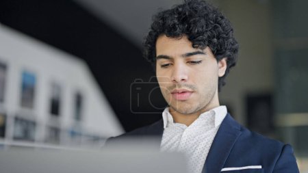 Téléchargez les photos : Jeune homme d'affaires latino-américain utilisant un ordinateur portable au bureau - en image libre de droit
