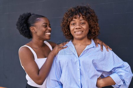 Foto de Mujeres afroamericanas madre e hija abrazándose sobre un fondo negro aislado - Imagen libre de derechos