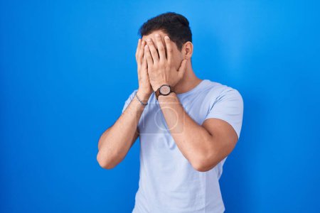 Photo for Young hispanic man standing over blue background with sad expression covering face with hands while crying. depression concept. - Royalty Free Image