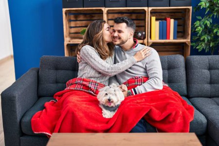 Photo for Man and woman hugging and kissing sitting on sofa with dog at home - Royalty Free Image