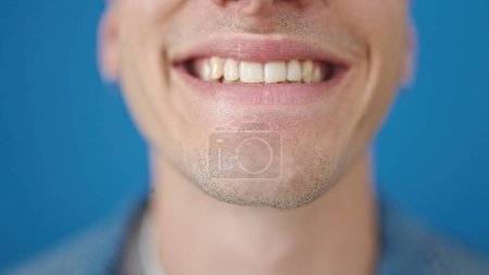 Téléchargez les photos : Jeune homme hispanique souriant confiant sur fond bleu isolé - en image libre de droit