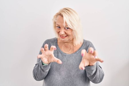 Téléchargez les photos : Moyen âge femme caucasienne debout sur fond blanc souriant drôle faisant griffe geste comme chat, expression agressive et sexy - en image libre de droit