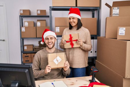 Photo for Two young people working at small business ecommerce at christmas winking looking at the camera with sexy expression, cheerful and happy face. - Royalty Free Image