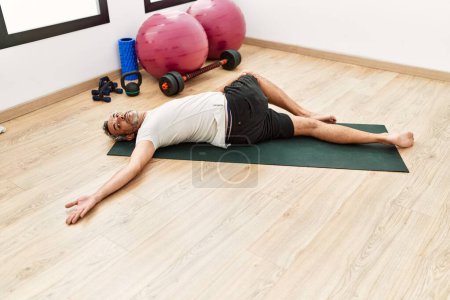 Photo for Middle age grey-haired man stretching back at sport center - Royalty Free Image