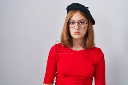 Téléchargez les photos : Jeune rousse femme debout portant des lunettes et béret déprimé et inquiet pour la détresse, pleurer en colère et peur. triste expression. - en image libre de droit