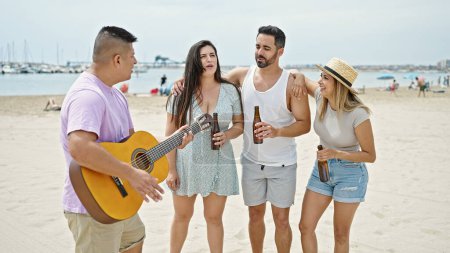 Foto de Grupo de personas tocando la guitarra bebiendo cerveza cantando canción en la playa - Imagen libre de derechos