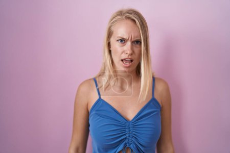 Photo for Young caucasian woman standing over pink background in shock face, looking skeptical and sarcastic, surprised with open mouth - Royalty Free Image