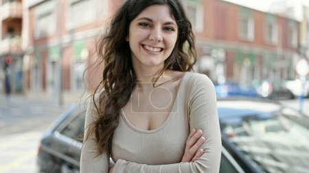 Téléchargez les photos : Jeune belle femme hispanique souriante confiante debout avec les bras croisés geste à la rue - en image libre de droit