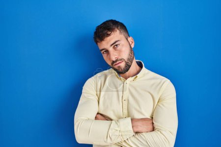 Photo for Handsome hispanic man standing over blue background looking sleepy and tired, exhausted for fatigue and hangover, lazy eyes in the morning. - Royalty Free Image