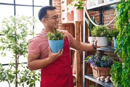 Photo for Young chinese man florist holding plant at florist - Royalty Free Image