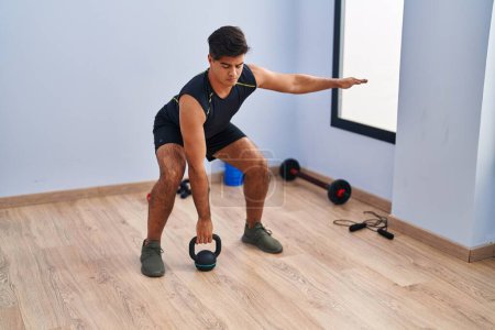 Photo for Young hispanic man using kettlebell training at sport center - Royalty Free Image