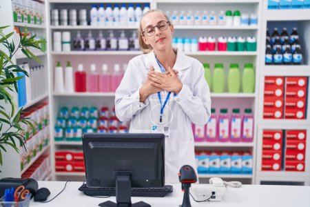 Photo for Young caucasian woman working at pharmacy drugstore smiling with hands on chest with closed eyes and grateful gesture on face. health concept. - Royalty Free Image