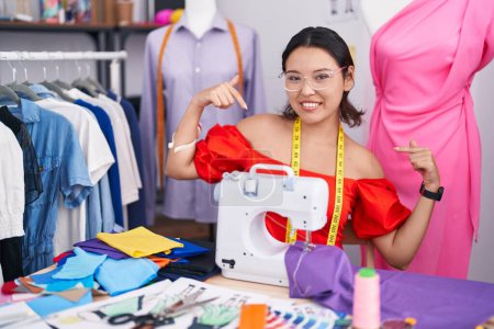 Photo for Hispanic young woman dressmaker designer using sewing machine looking confident with smile on face, pointing oneself with fingers proud and happy. - Royalty Free Image