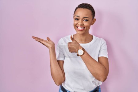 Photo for Beautiful african american woman standing over pink background showing palm hand and doing ok gesture with thumbs up, smiling happy and cheerful - Royalty Free Image
