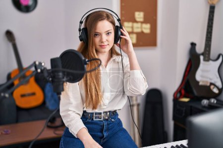 Photo for Young caucasian woman recording song at music studio thinking attitude and sober expression looking self confident - Royalty Free Image